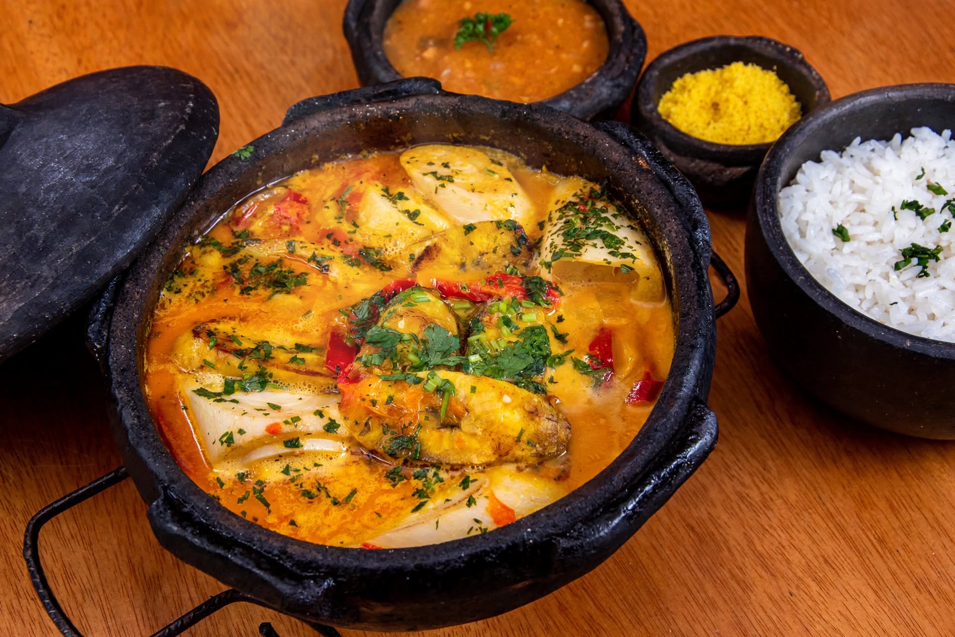 Moqueca de tambaqui na panela de barro com pirão, arroz branco e farofa, típica da gastronomia regional servida no Paraíso dos Tambaquis em Estância, Sergipe